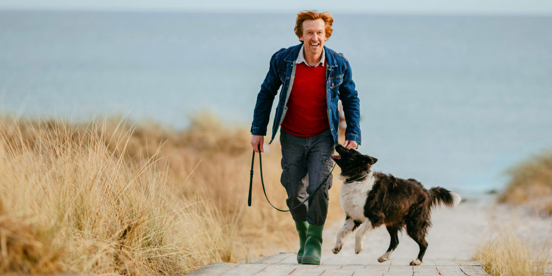 Man with dog on path by beach